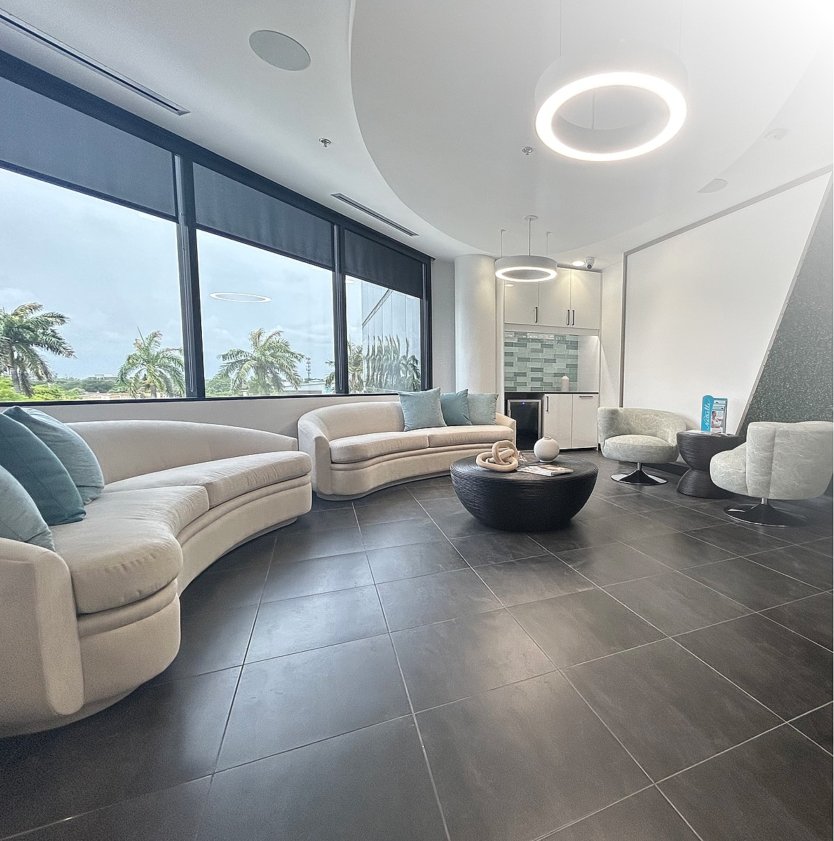 Modern lounge with circular furniture and windows.